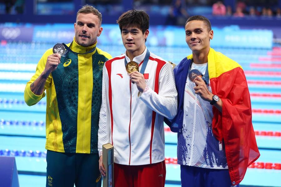 Înotătorul Pan Zhanle, medaliat cu aur în proba de 100 de metri liber la Jocurile Olimpice de la Paris 2024, încadrat de Kyle Chalmers și David Popovici / Foto: Getty Images Un campion olimpic american crede că David Popovici poate doborî recordul mondial la 200 m liber: „Este deja unul dintre cei mai mari înotători din toate timpurile” + Ce crede despre legitimitatea bornei stabilite de Pan Zhanle la Paris