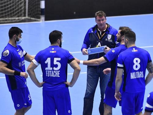 Antrenorul Eliodor Voica dă indicații la time out. Pe tricourile jucătorilor se observă banderolele albe FOTO sportpictures.eu