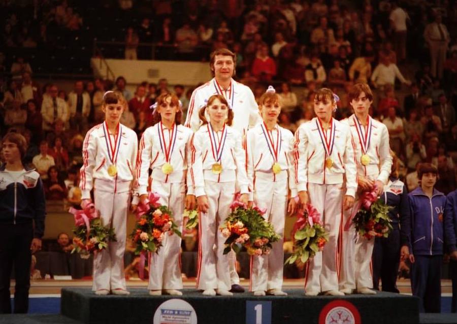 Bela Karoly pe podiumul mondial de la Fort Worth, alături de fetele care au cucerit primul titlu suprem pe echipe din istoria gimnasticii românești 10 episoade cu Bela Karolyi, antrenorul Nadiei Comăneci, care a decedat noaptea trecută: de la bătăile crunte aplicate sportivelor până la „clientul” Securității lui Ceaușescu