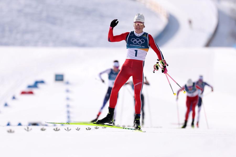 Johannes Klaebo trecând linia de sosire primul la 10 + 10 km schiatlon la JO 2026 Foto: Guliver/GettyImages Schiorul norvegian care caută gloria olimpică supremă și „arma sa secretă” în vârstă de 83 de ani
