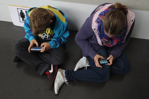 Doi copii din Germania se joacă pe telefoanele mobile, foto: Guliver/gettyimages