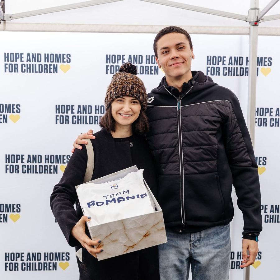 David Popovici alături de câștigătoarea echipamentului purtat la Paris David Popovici a pus prima cărămidă la casa celor 11 copii pentru care și-a donat echipamentul de la Paris