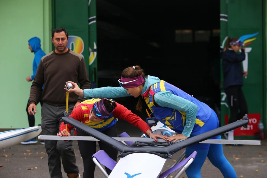 Ancuța Bodnar și Simona Radiș fac măsurători cu o ruletă sub ochii antrenorului Marcus Despina. FOTO: Dumitru Angelescu Ies bărcile sub ceața Snagovului » Lotul național de canotaj se pregătește pentru calificările la JO de la Paris