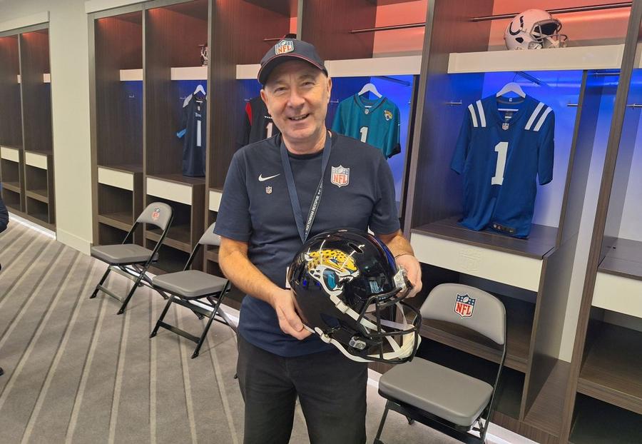 Larry Coach, pozând cu casca lui Jacksonville Jaguars, echipa sa favorită de fotbal american, în vestiarul NFL de pe ”Tottenham Hotspur Stadium” Foto: GSP Surpriză totală pe stadionul lui Tottenham » Un american îndrăgostit de România povestește pentru GSP: „Am vrut să fiu Florea Dumitrache. A fost eroul meu