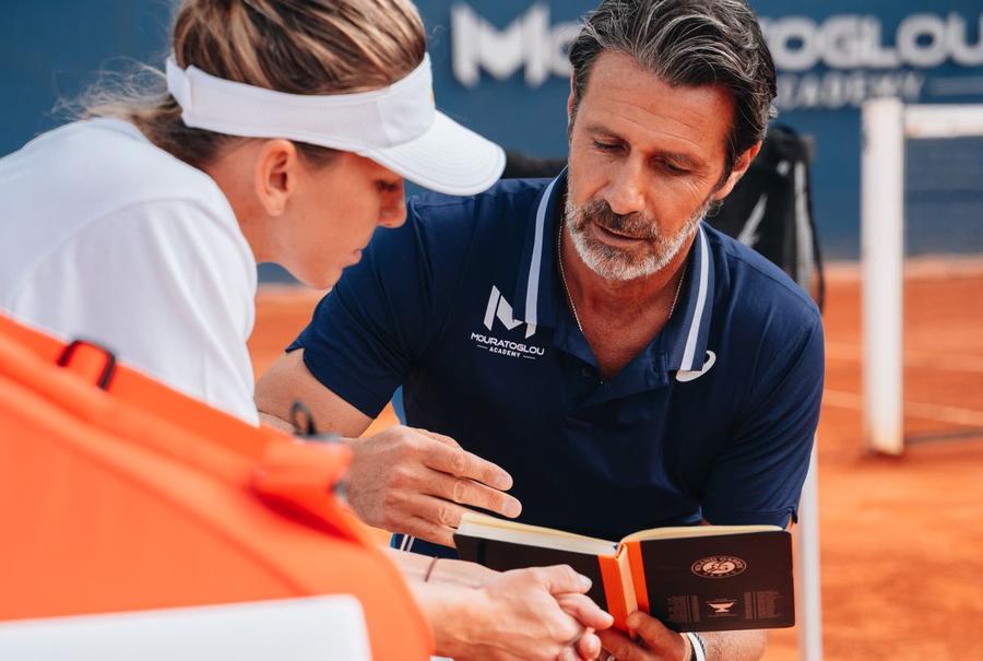Patrick Mouratoglou vorbindu-i Simonei Halep și consultându-și agenda, el fiind renumit pentru însemnările și fișele pe care le face despre jucătorii săi FOTO Mouratoglou Academy Imperiul Patrick Mouratoglou » Antrenorul lui Halep a explicat pentru GSP cum a clădit o rețea incredibilă în tenis: „Avem 4000 de jucători, cea mai mare bază din Europa”