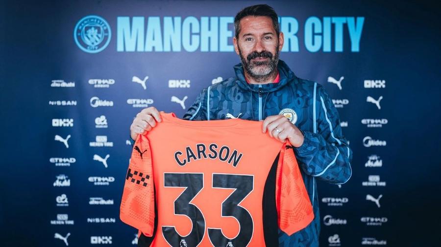 Scott Carson, pozând cu tricoul cu 33 pe spate, la anunțul oficial al reînnoirii acordului cu City / Foto: X Manchester City La 38 de ani și niciun minut jucat la Manchester City, a prelungit până în 2025. Explicația incredibilă