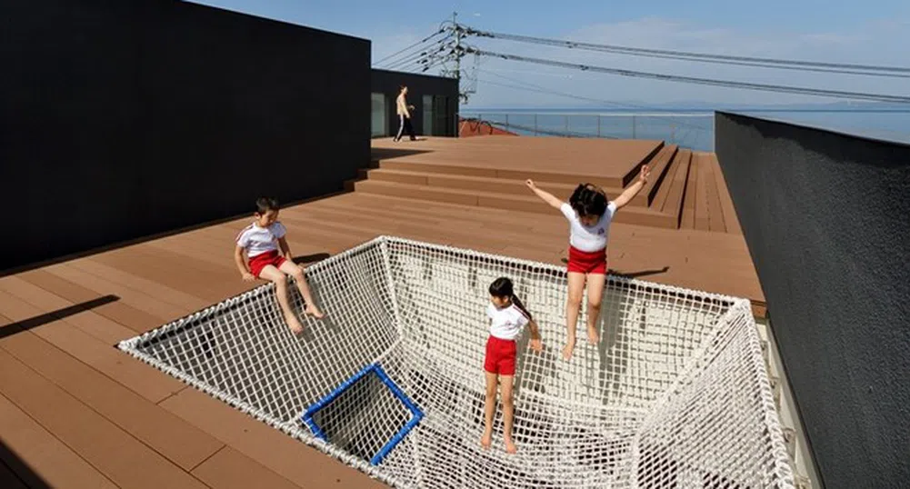 Японска детска градина с покрив за игри и изглед към океана