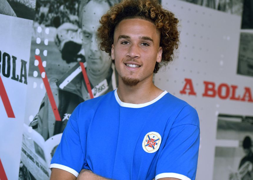 Afonso Pinto sorri, de braços cruzados, com uma camisola do Belenenses e na redação de A BOLA