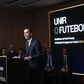 Imagem de Pedro Proença a dicursar na manhã de segunda-feira, 3 de fevereiro, durante a apresentação da sua candidatura à presidência da Federação Portuguesa de Futebol. «Unir a comunidade do futebol» é o que se lê em pano de fundo