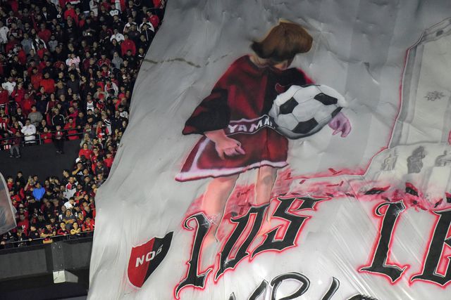 Bandeira dos adeptos do Newells Old Boys com desenho de Messi a dar toques em criança