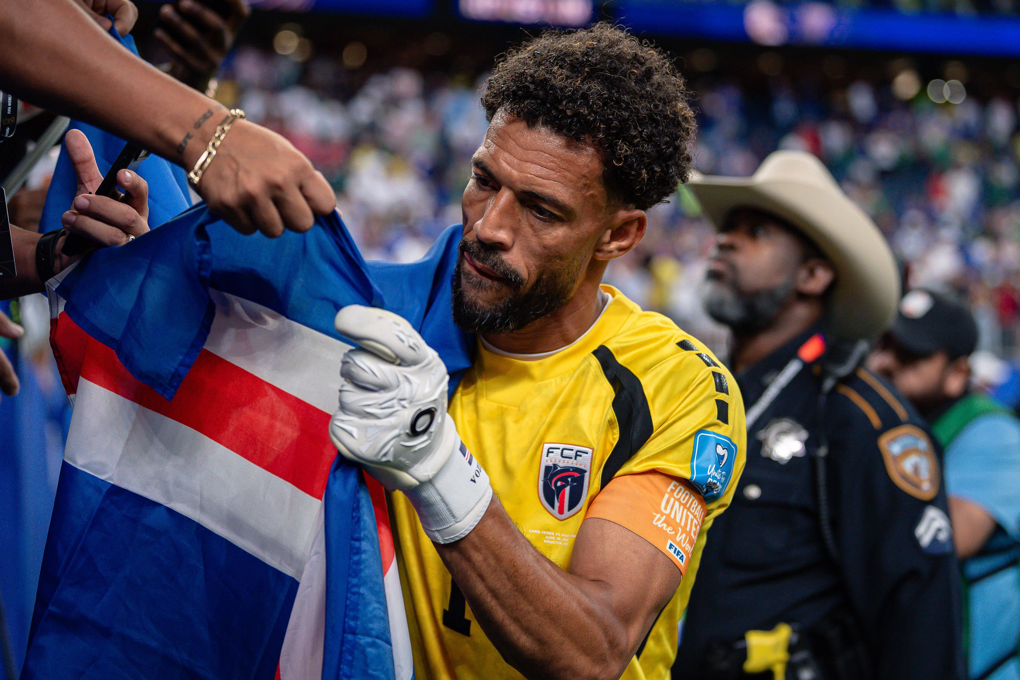 Vozinha a dar autógrafo em bandeira de Cabo Verde