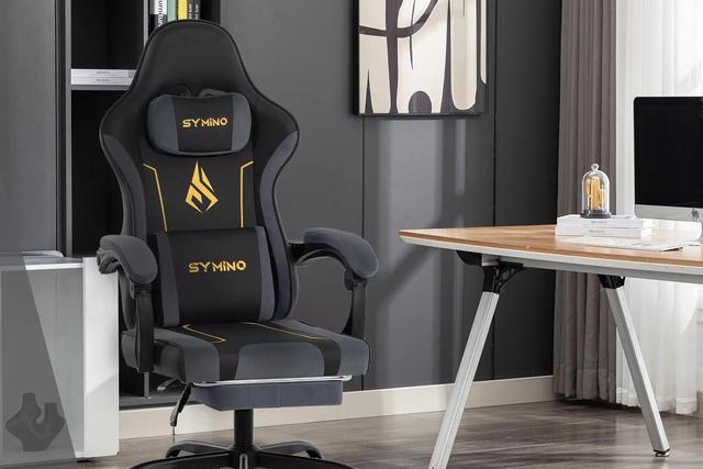 Cadeira gamer ergonómica Symino, com apoio lombar e cervical, posicionada num escritório moderno.