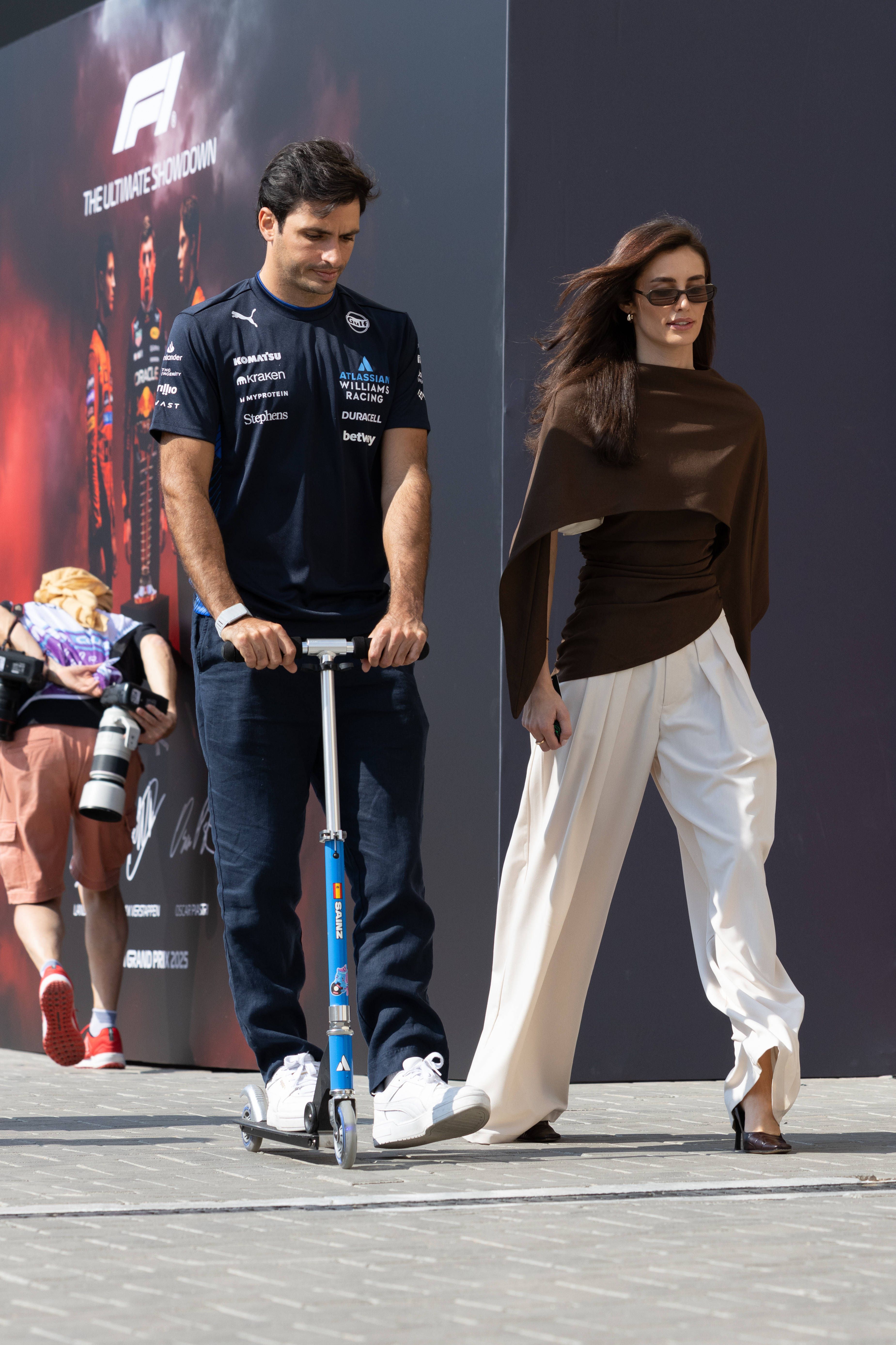 Carlos Sainz chega de trotineta acompanhado pela namorada, Rebecca Donaldson