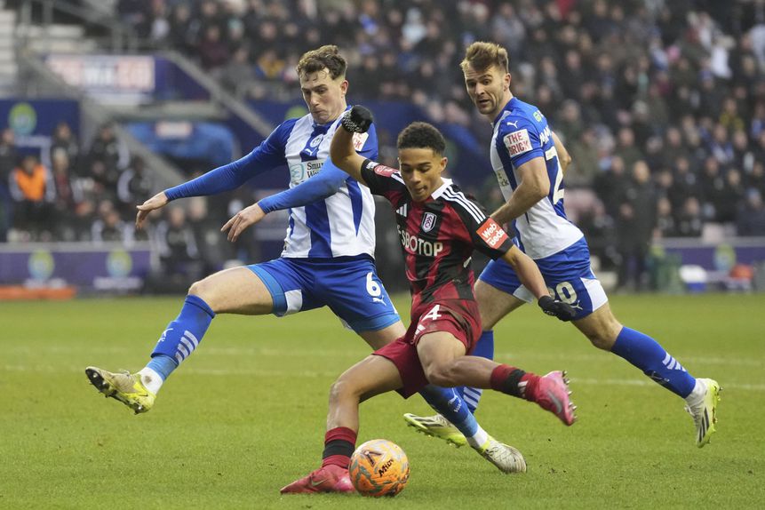 Joshua King remata perante a pressão de um defesa dos Latics