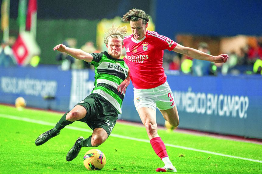 Carreras, defesa-esquerdo do Benfica, tenta ultrapassar Hjulmand, médio do Sporting, que tenta um tackle para desarmar o espanhol das águias