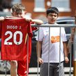 Jovem adepto do Liverpool a segurar a camisola número 20 de Diogo Jota