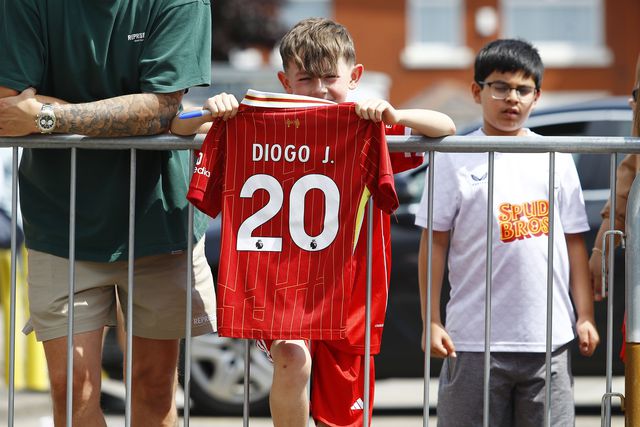 Jovem adepto do Liverpool a segurar a camisola número 20 de Diogo Jota