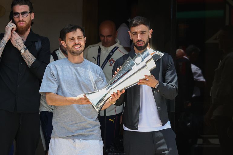 Bernardo Silva e Bruno Fernandes no aeroporto, com o troféu da Liga das Nações (Lusa)