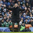 Pep Guardiola, treinador do Manchester City, de braços abertos virado para o relvado