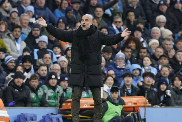 Pep Guardiola, treinador do Manchester City, de braços abertos virado para o relvado