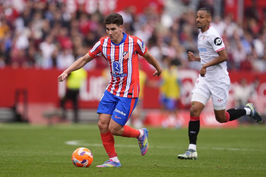 Julián Alvarez, avançado argentino do Atlético de Madrid, controla a bola perante a oposição, ainda que a alguma distância, de um jogador do Sevilha