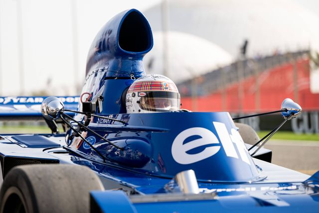 Sir Jackie Stewart no carro em que foi campeão mundial, com um capacete assinado por vários campeões