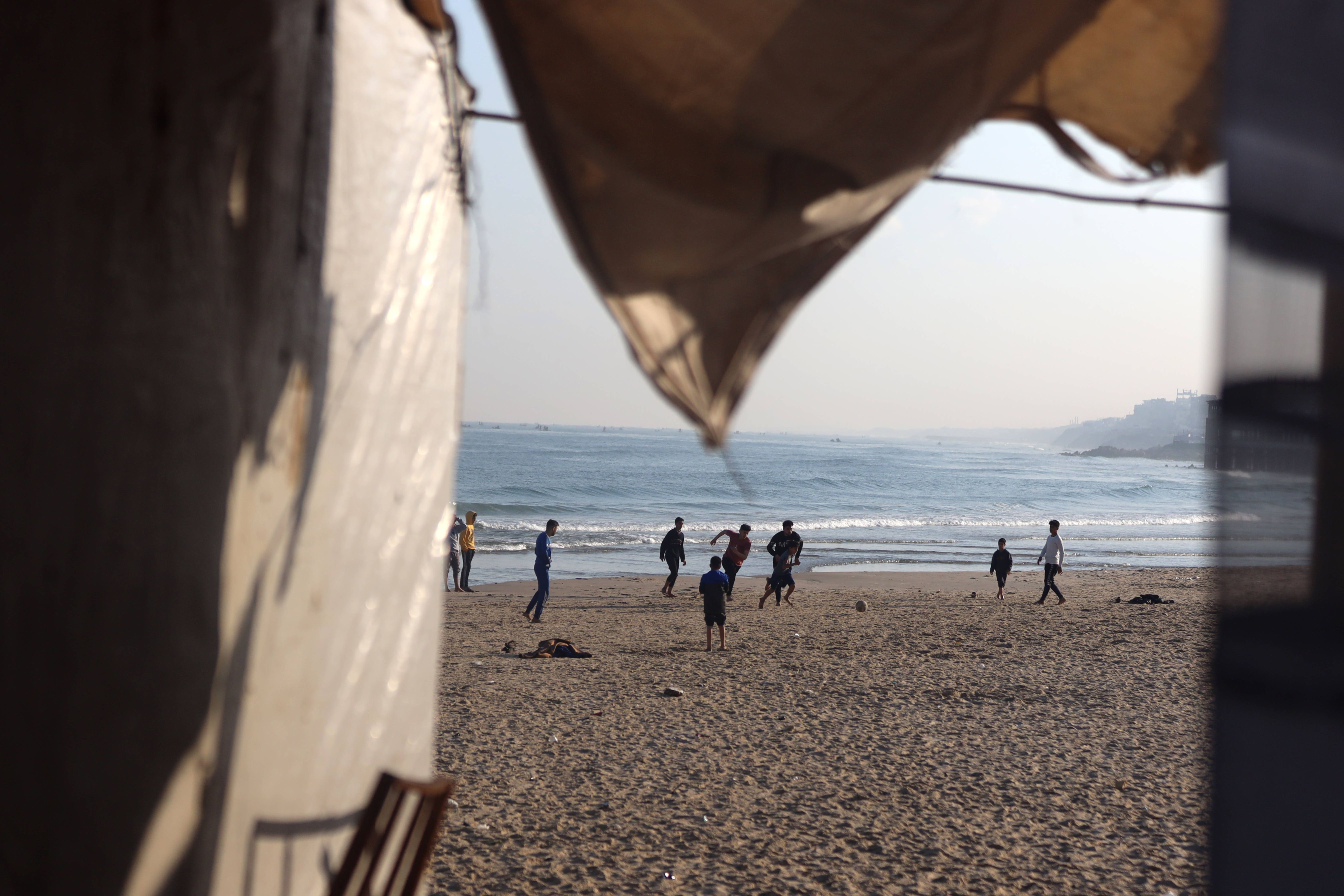 Crianças palestinianas jogam futebol numa praia na faixa de Gaza