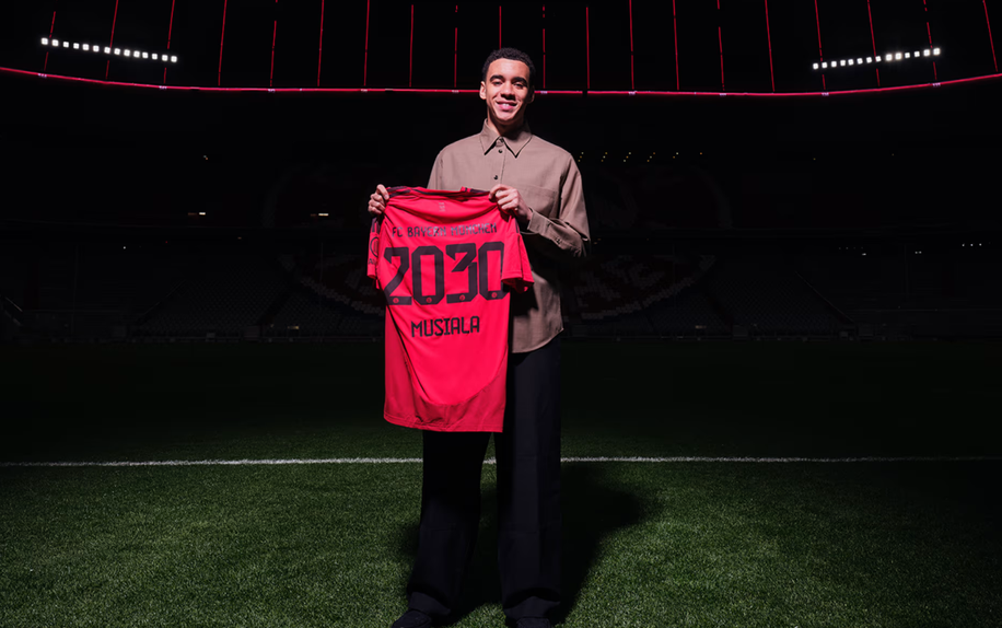 Foto do anúncio de renovação de Musiala com o Bayern, segurando a camisola com o número 2030, validade do contrato