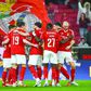 Jogadores do Benfica festejam, com uma bandeira dos encarnados como pano de fundo, um golo marcado no Estádio da Luz