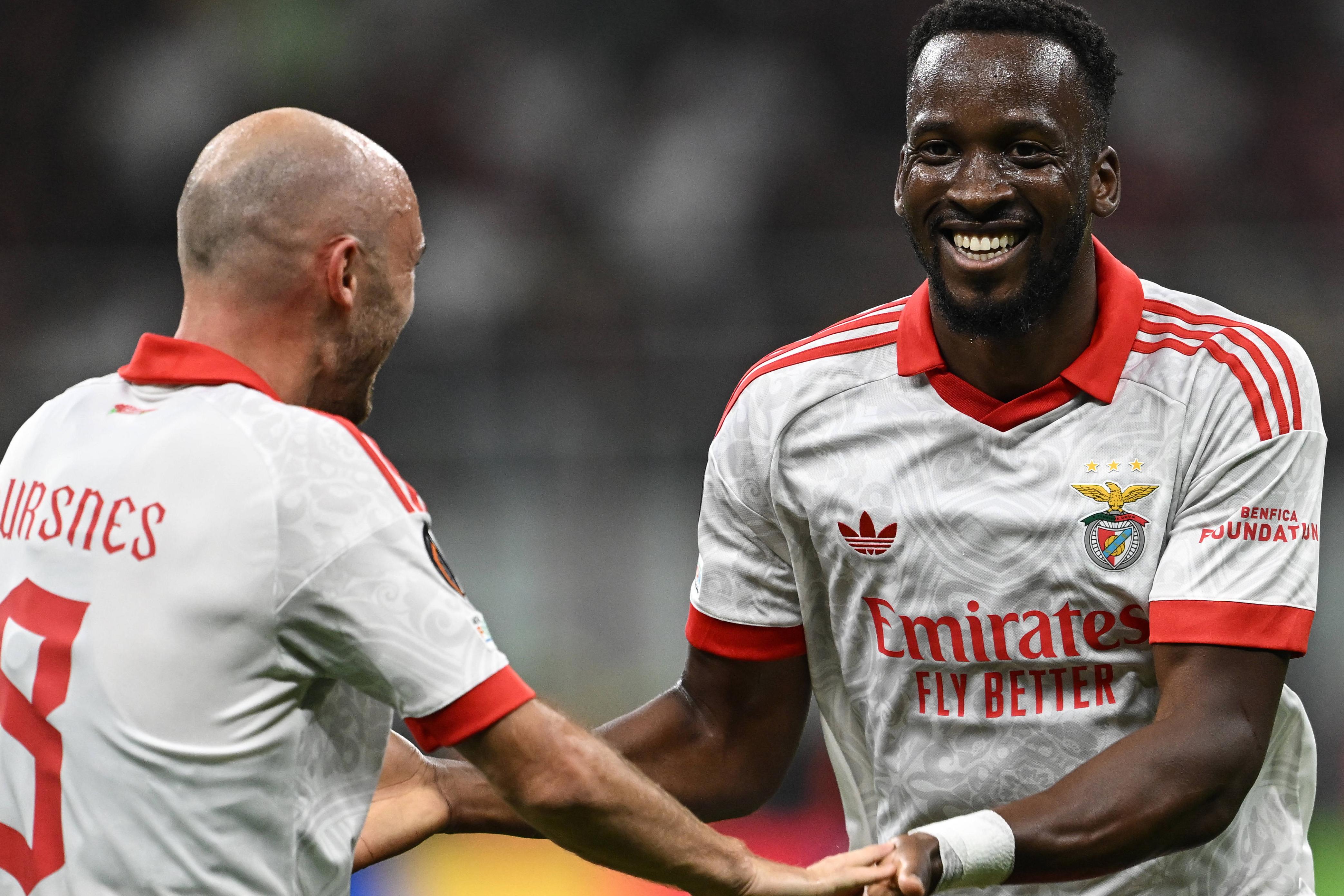 Lukebakio, sorridente e cumprimentado por Aursnes, depois de ter marcado o primeiro golo do Benfica na vitória sobre o Milan — Foto: IMAGO