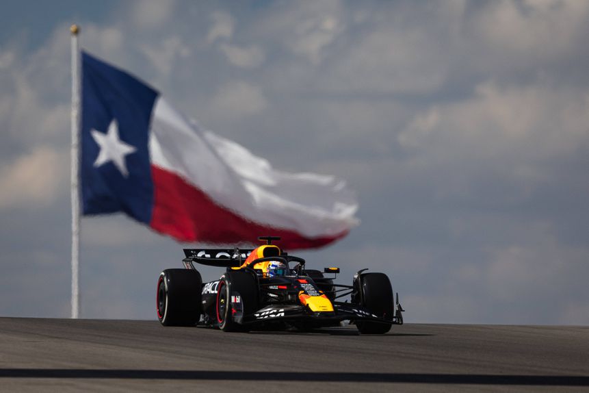 Max Verstappen no carro da Red Bull com a bandeira do Texas atrás