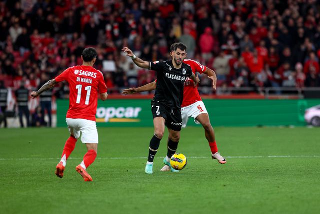 Nélson Oliveira, avançado do V. Guimarães, tem a bola controlada e procura fugir à marcação apertada de Bah (defesa do Benfica que atualmente recupera de lesão), sendo que Di María está na expectativa