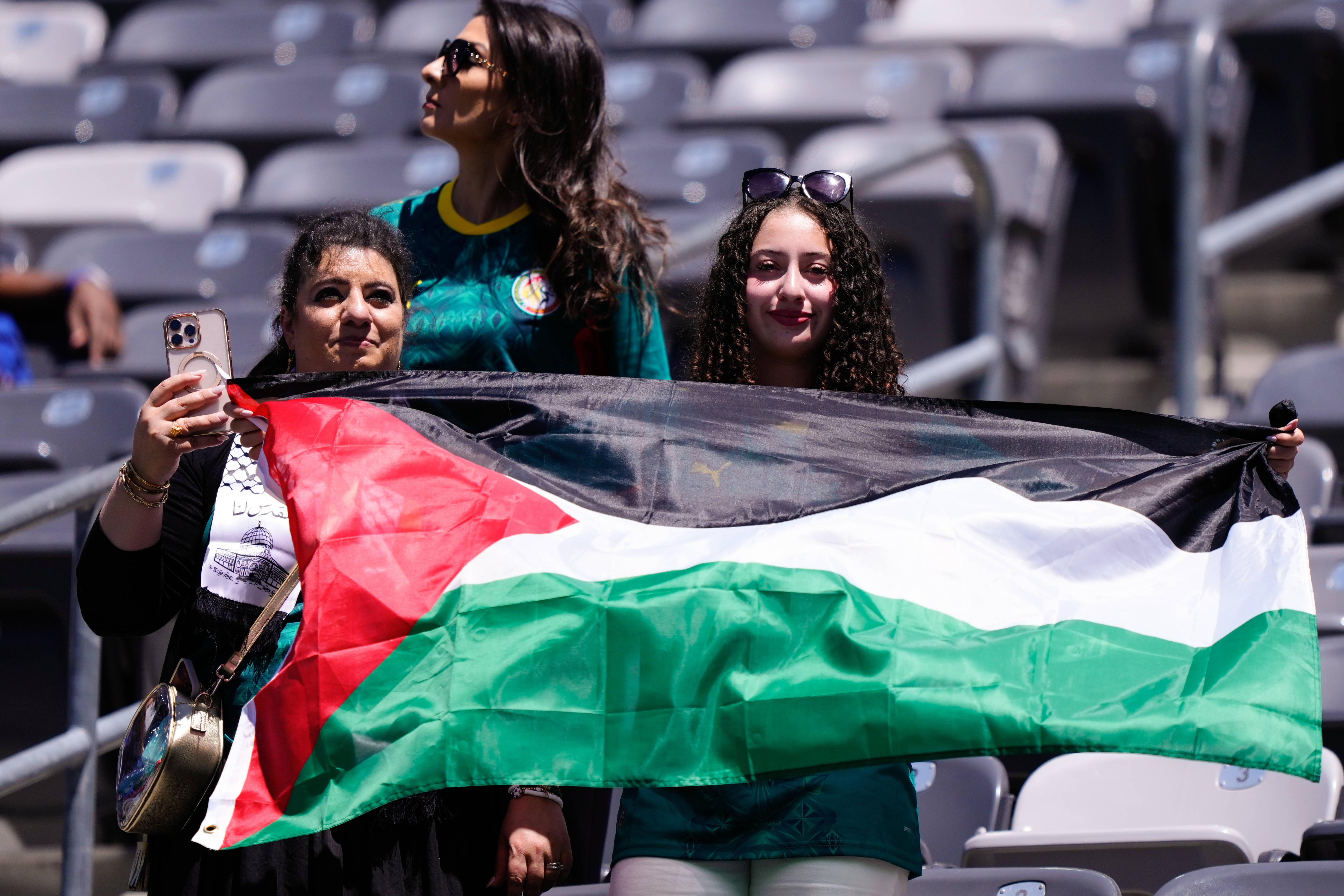 Adeptas seguram bandeira da Palestina no encontro entre França e Senegal no Mundial 2026