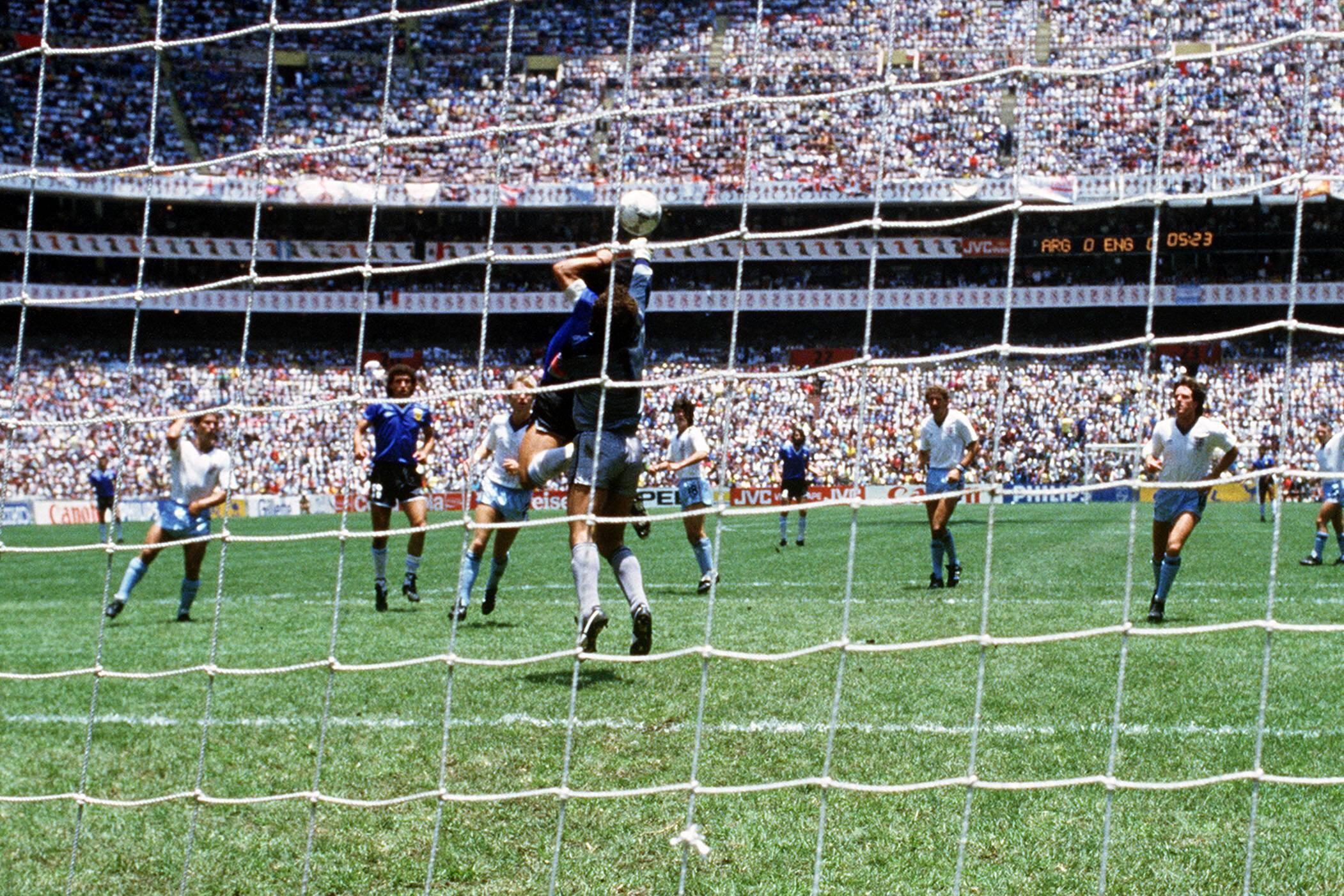 Momento em que Maradona toca a bola com a mão, abrindo o marcador no jogo entre Argentina e Inglaterra, dos quartos de final do Mundial 1986 - Foto: IMAGO