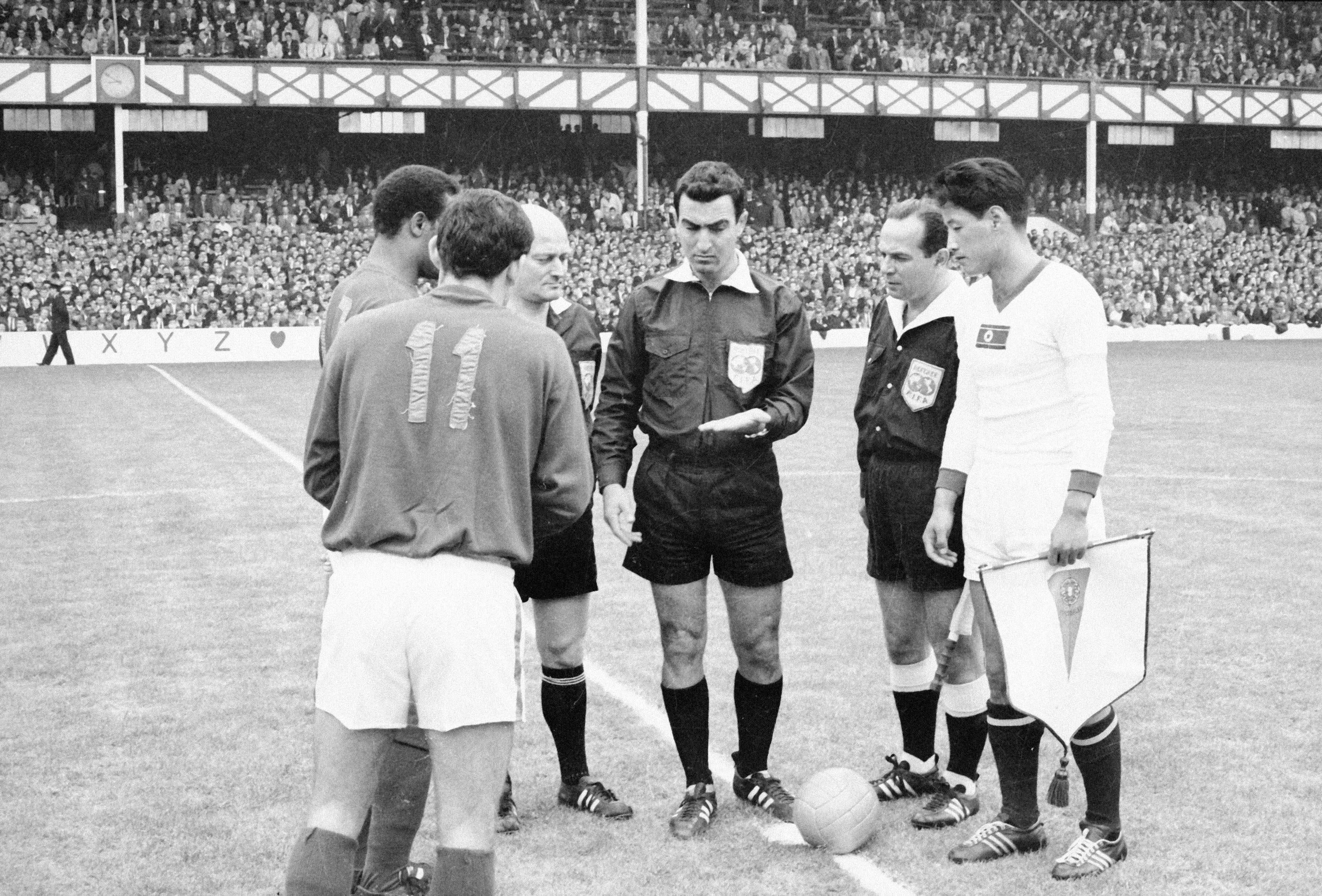 Mário Coluna, capitão da Seleção Nacional, troca galhardetes com Shin Yung Kyoo, capitão coreano, na presença do árbitro israelita Menachen Ashkenael, no Portugal-Coreia do Norte (5-3), de 1966, em Goodison Park - Foto: A BOLA