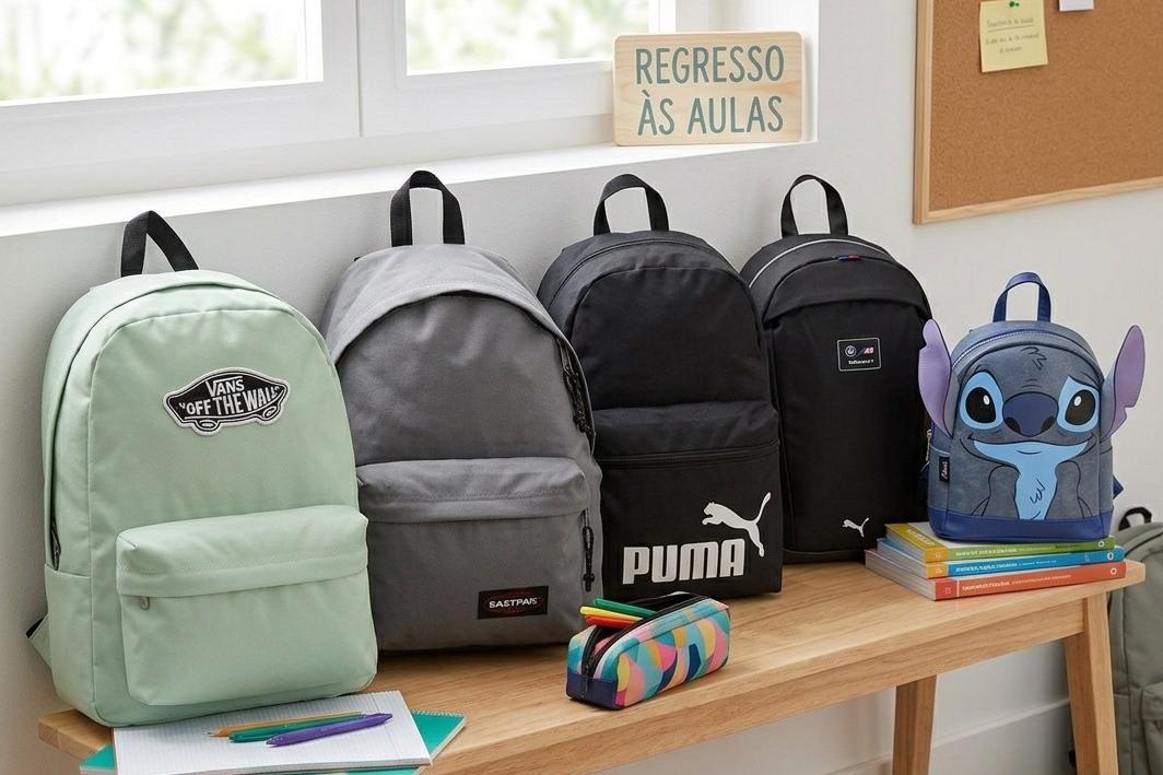 Cinco mochilas alinhadas sobre um banco de madeira, representando o tema de regresso às aulas.