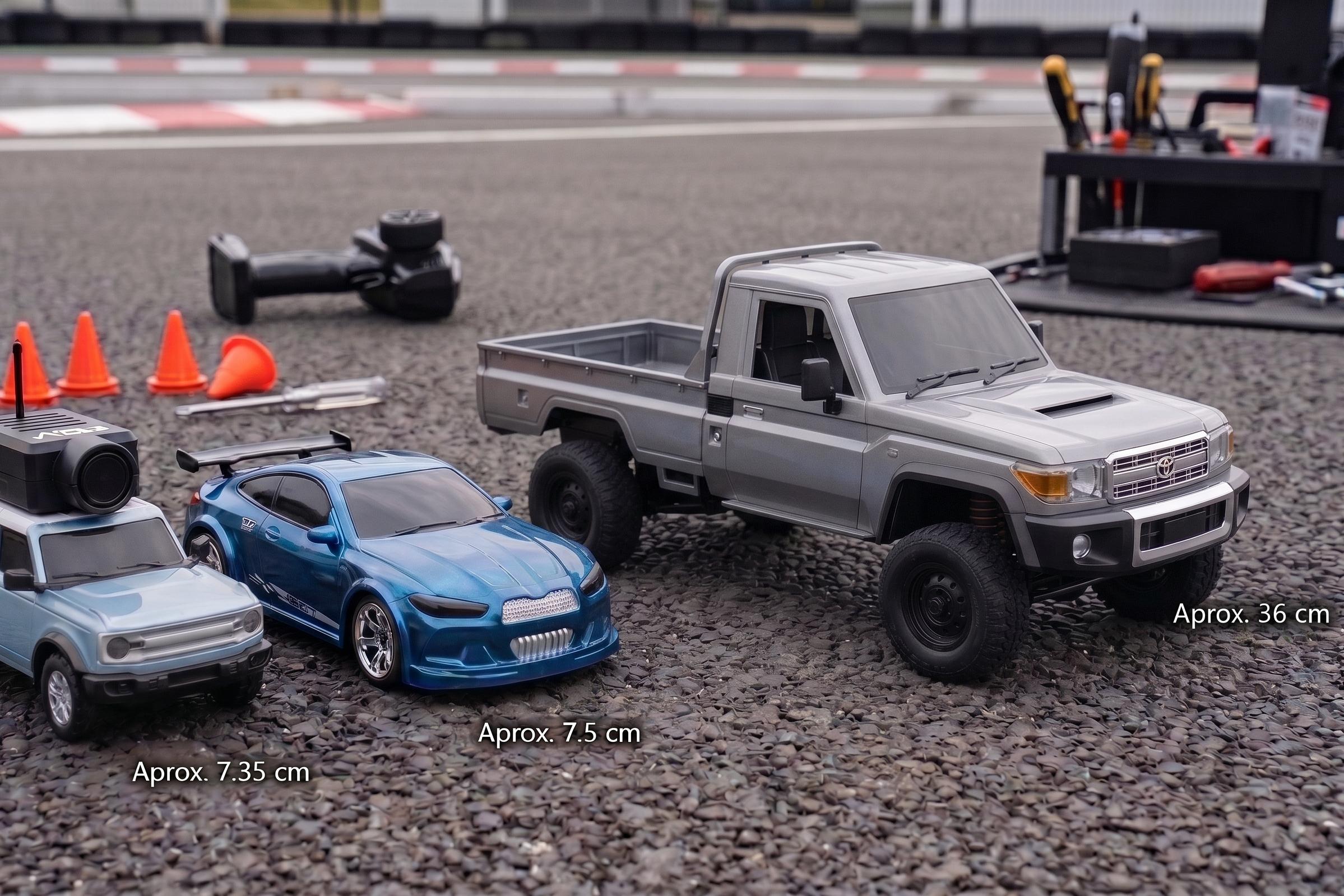 Três carros de controlo remoto de diferentes modelos e tamanhos, alinhados lado a lado numa superfície de asfalto. No fundo, desfocados, estão pequenos cones de trânsito, um comando à distância e algumas ferramentas.
