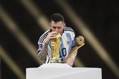 Lionel Messi a beijar o troféu de campeão do mundo e com o prémio de melhor jogador da competição em 2022