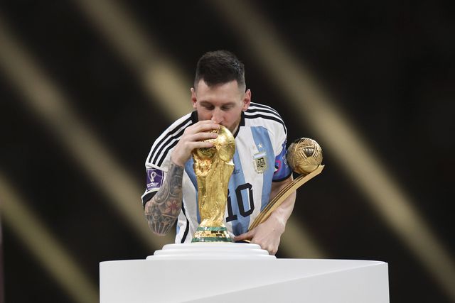 Lionel Messi a beijar o troféu de campeão do mundo e com o prémio de melhor jogador da competição em 2022