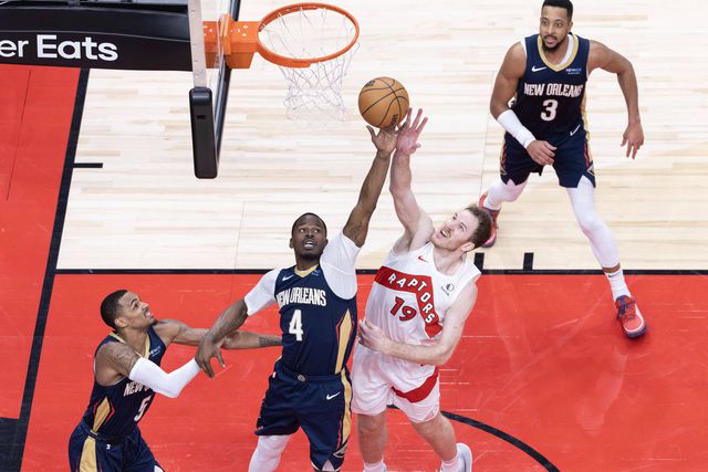 Javonte Green, dos New Orleans Pelicans, luta pelo ressalto com Jakob Poeltl, dos Toronto Raptors, durante o jogo entre as duas equipas