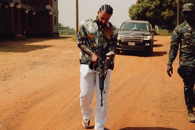 Memphis Depay segura uma espingarda, acompanhado de um militar