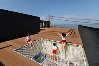 Японска детска градина с покрив за игри и изглед към океана