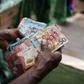 A street vendor counts Ghanaian cedi currency banknotes.Photographer: Ernest Ankomah/Bloomberg