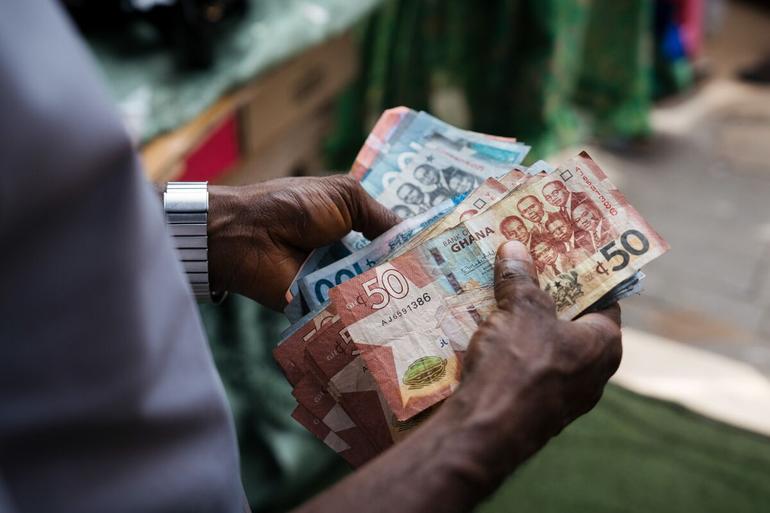 A street vendor counts Ghanaian cedi currency banknotes.Photographer: Ernest Ankomah/Bloomberg