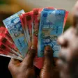 A man holds Ghana’s cedi notes in Accra July 3, 2007. REUTERS/Luc Gnago (GHANA)