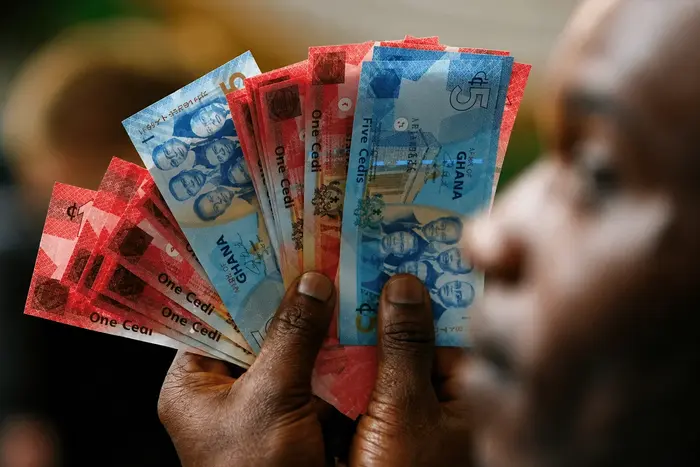 A man holds Ghana’s cedi notes in Accra July 3, 2007. REUTERS/Luc Gnago (GHANA)