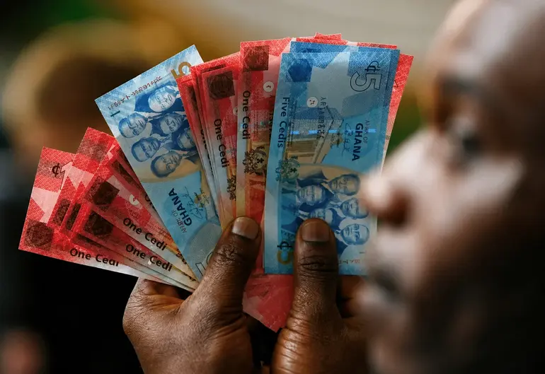 A man holds Ghana’s cedi notes in Accra July 3, 2007. REUTERS/Luc Gnago (GHANA)