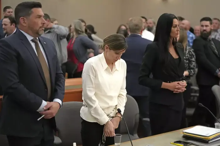 Kouri Richins, center, a Utah mother of three who authorities say fatally poisoned her husband then wrote a children’s book about grieving, stands in court Monday in Park City, Utah. (Rick Bowmer / Associated Press)