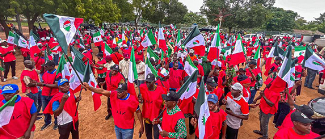 Nigerian workers in red NLC vests waving flags during a May Day solidarity march.