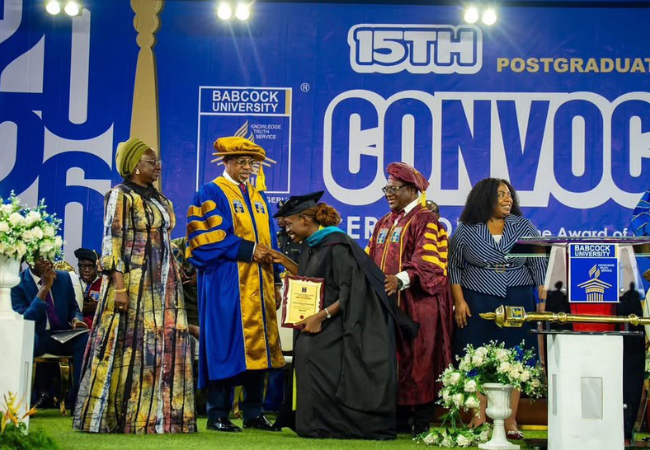 Ayotundun Christianah Ojelabi receiving an award plaque on stage during Babcock University's 15th Postgraduate Convocation ceremony.